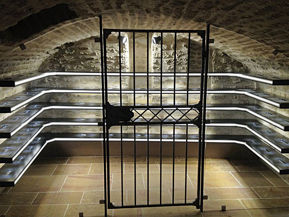Cave à vin voûtée avec grille en fer forgé et éclairage LED