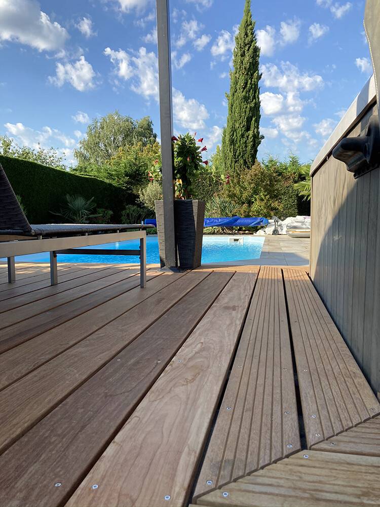 Terrasse en bois exotique avec spots LED au bord d'une piscine