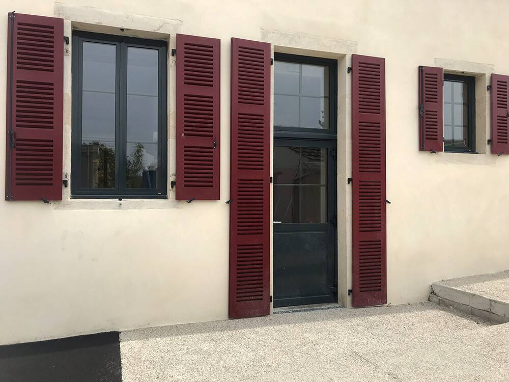 Fenêtres aluminium grises et volets battants bordeaux